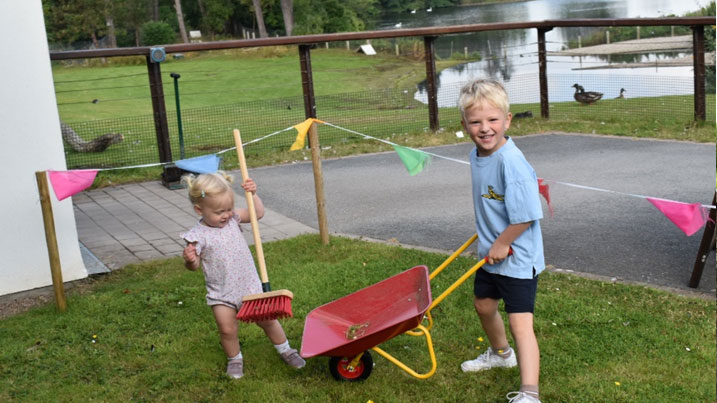 Boy with a wheelbarrow taking part in WWT's Wetland Ranger activity of cleaning up after the ducks