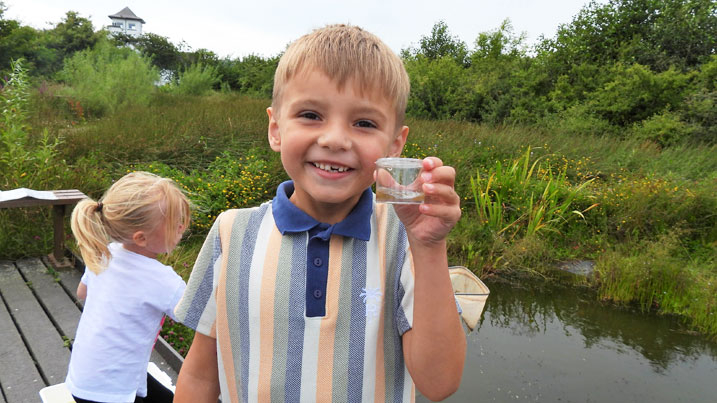 Boy holding up a jar of his pond dipping discoveries