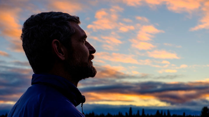 Man looking up into the sky, pretty with pink and orange clouds 