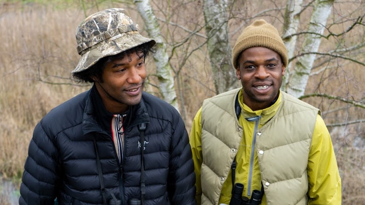 Ollie Olanipekun and Nadeem Perera, founders of Flock Together, outdoors in hats and coats in front of a tree