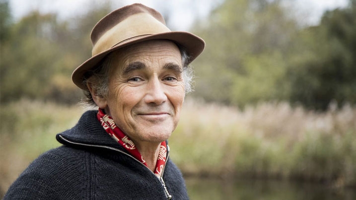 Head and shoulders shot of Sir Mark Rylance with a wetland background