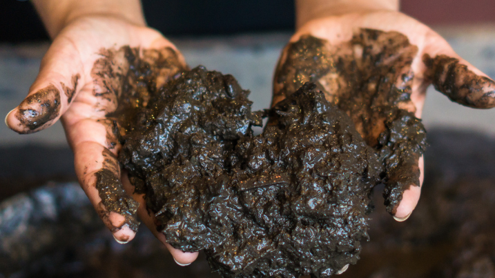 A young child happily playing with squishy mud in their hands