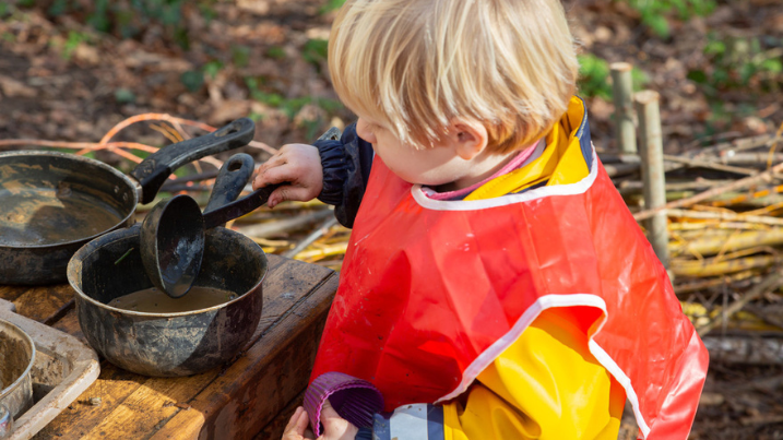 a child happily making some muddy food in the Mudfest kitchen