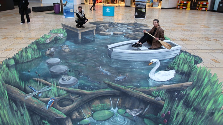 WWT's 3D wetlands mural in a shopping centre in Bristol with two people interacting with it