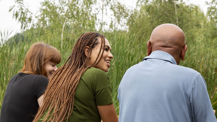 Three people with their backs to the camera, looking over a wetland