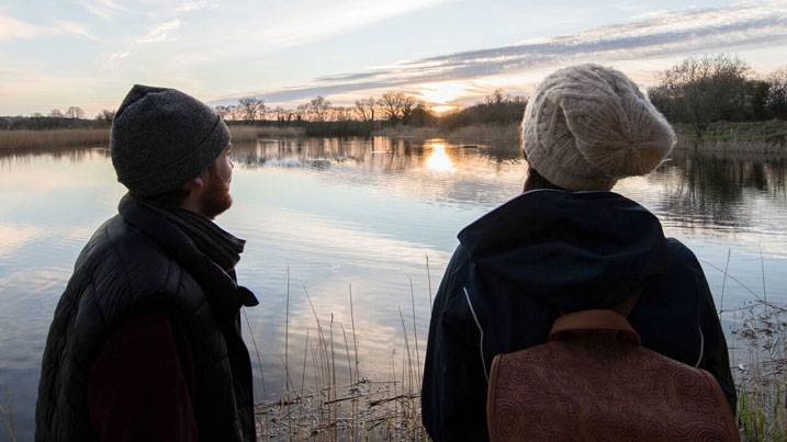 Two people overlooking a calm, tranquil lake