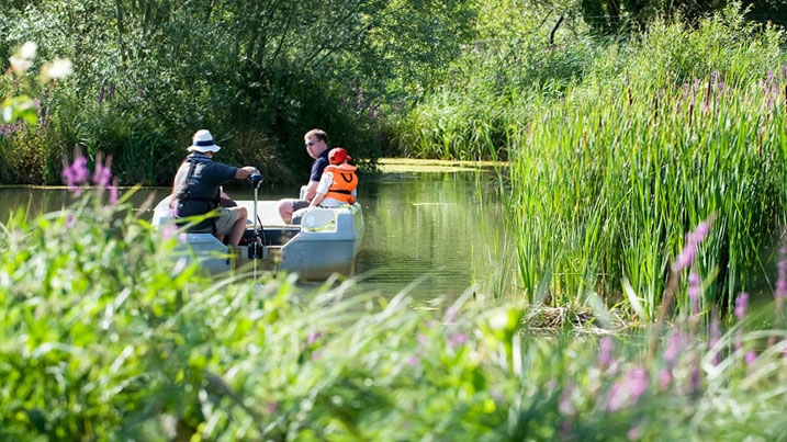 A family in a boat on the water, enjoying the boat safari at WWT Arundel