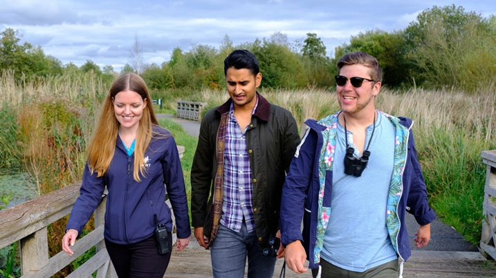 A WWT staff member walking with two visitors through the wetlands