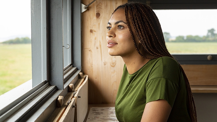 A woman in a bird hide looking out the window into the distance