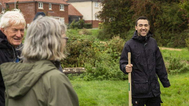 A man stood in a field smiling at two other older adults