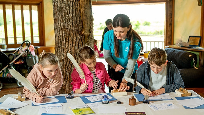 A group of children sat around a craft table writing stories