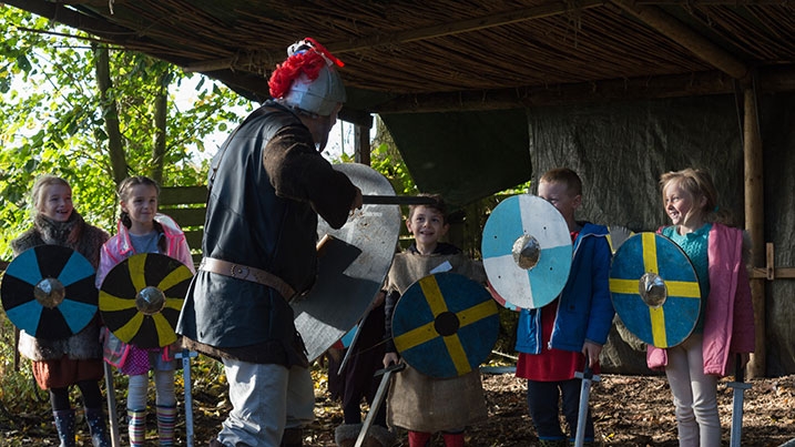 A group of children dressed in medieval clothing participating in a workshop
