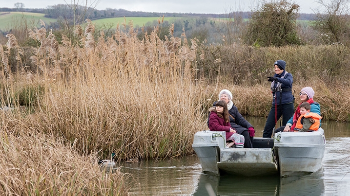 family dressed in winter clothing on a boat at WWT Arundel
