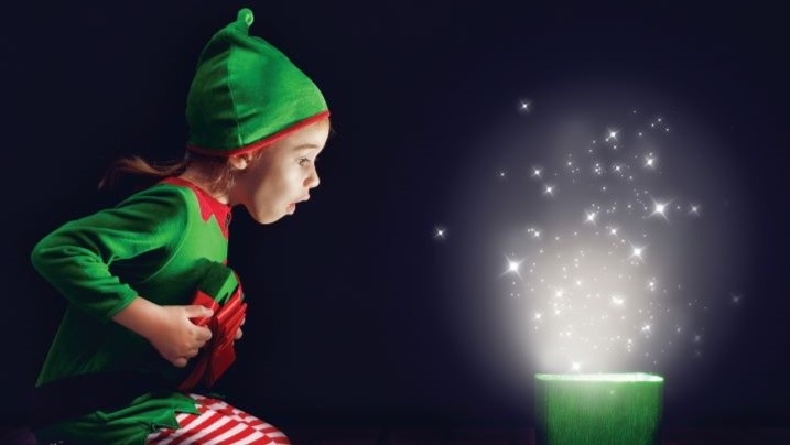 Child dressed as an elf opening a present