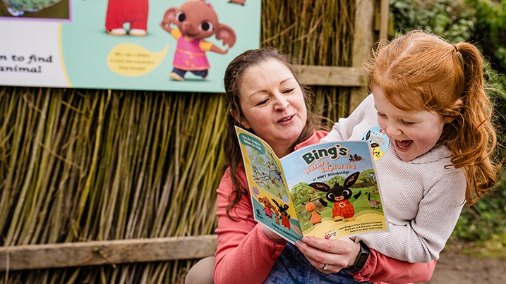 A family reading a trail guide with Bing and Flop on the front cover