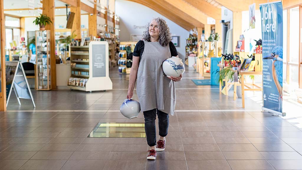 Tracey Johnston walking through the centre at WWT Castle Espie holding two vases