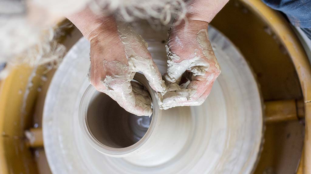 A pot being thrown on a wheel, by the hands of Tracey Johnston.