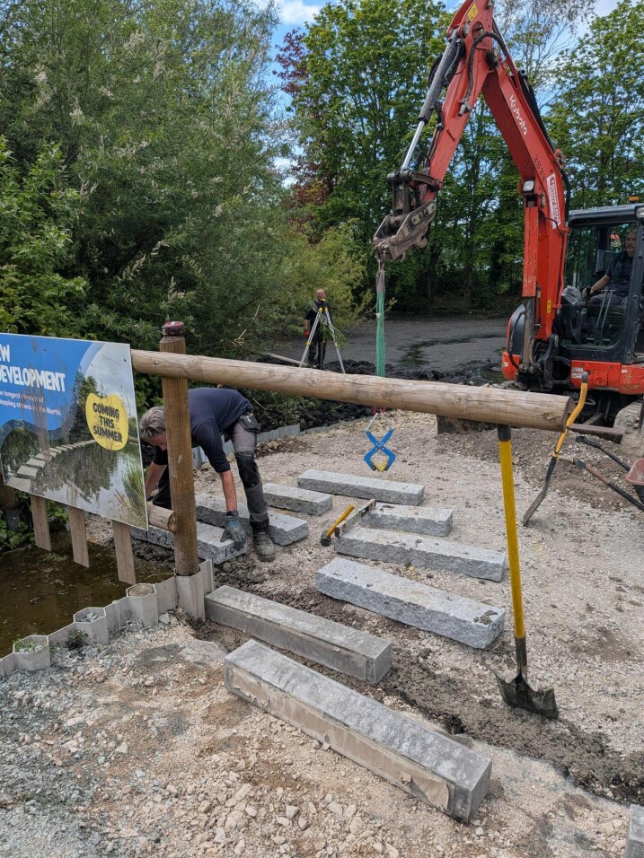 Facilities team member placing down the first stepping stone on concrete
