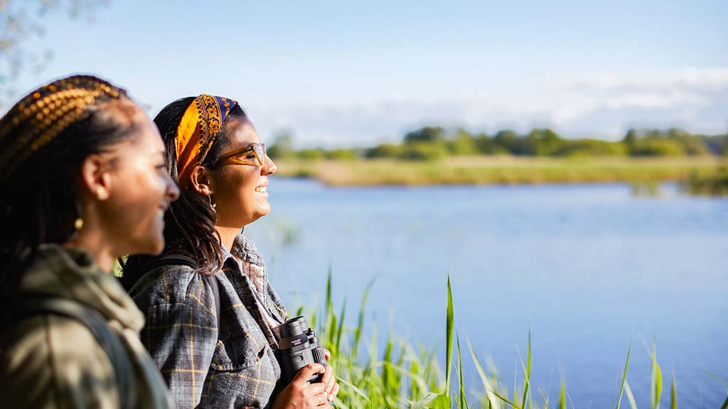 Wetland visitors smiling while looking out over a lake