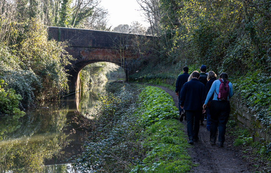 A group of people walk alongside a canal